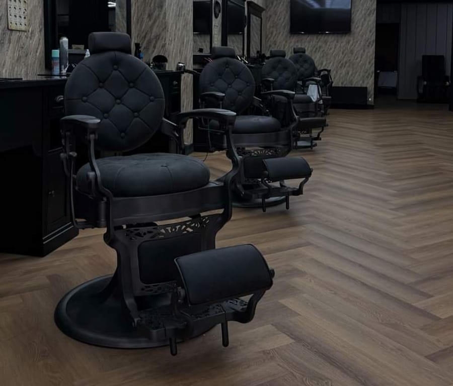 De voorste zwarte barberstoel met gecapitonneerde rugleuning op de visgraatvloer