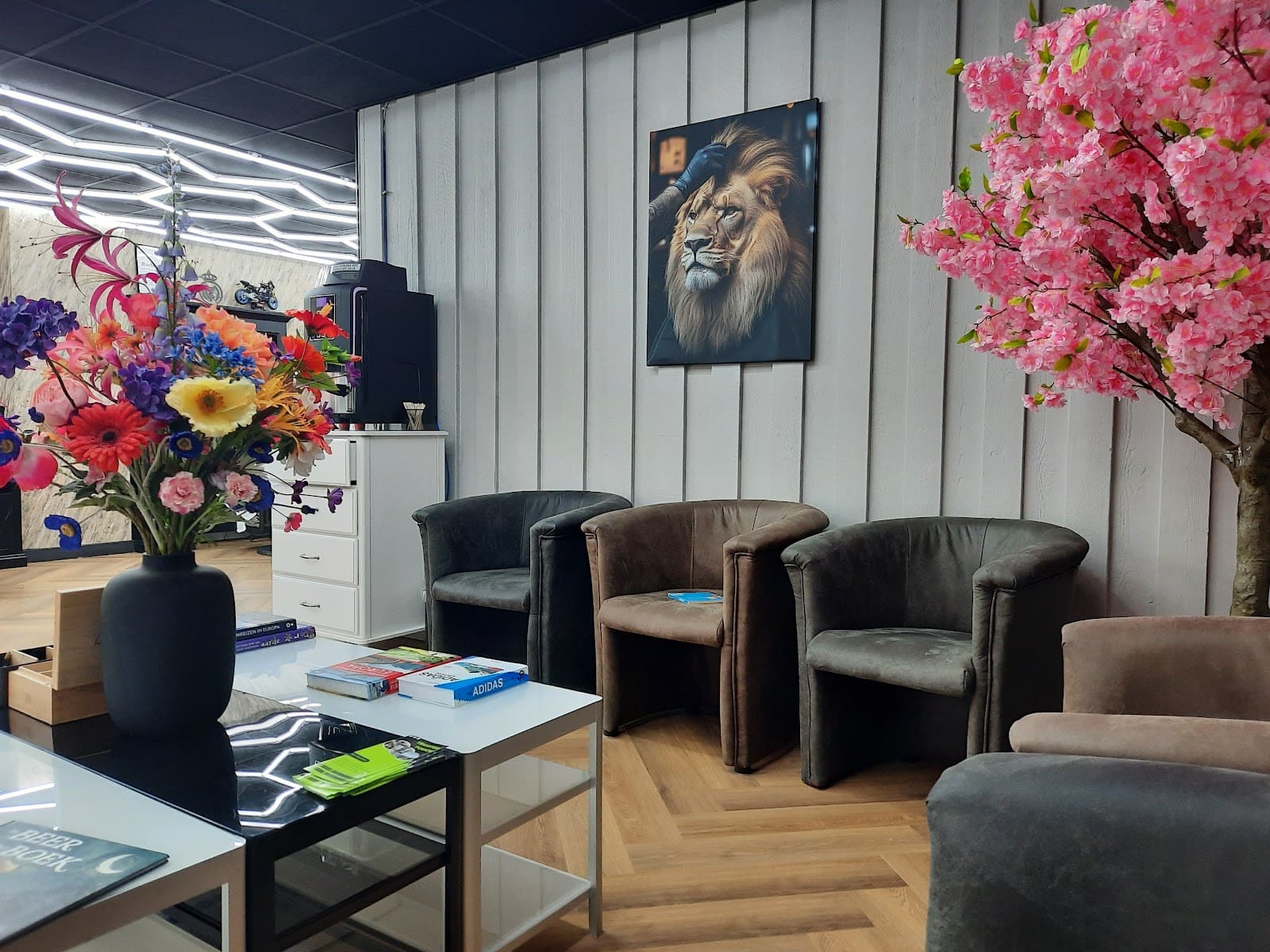 De wachthoek met leren fauteuils, tijdschriften, een koffiemachine en een roze bloesemboom